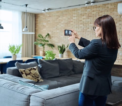 Agent immobilier qui prend en photo un élément du logement avec son téléphone